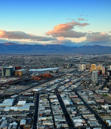 Las Vegas panorama at sunset with mountain, highway, street and luxury hotels.